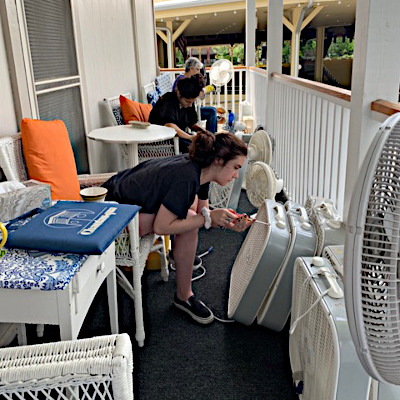 woman on shaw porch fixing box fans to be available for residents